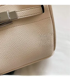 Close-up of beige lychee grain leather handbag with silver metal turn-lock detail