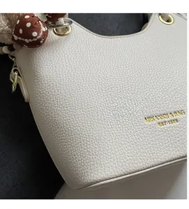 Detailopname van witte handtas met lycheetextuur, gouden ring en gestipte zijden sjaal
