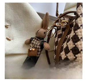 Détail d'un charm lapin en tricot marron avec motif pied-de-poule et métal doré