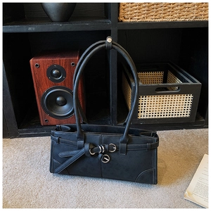 Détail d'un sac porté épaule vintage noir avec boucles argentées et texture mate