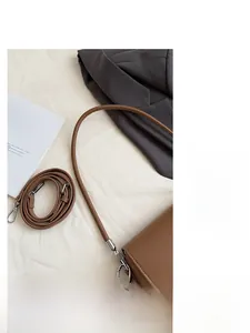 Dettaglio dei cinturini della borsa in pelle marrone con ganci in metallo argentato