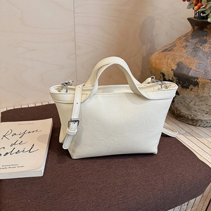 Detail of a creamy white leather tote bag with adjustable strap and metallic hardware