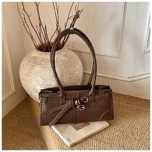 Gros plan sur un sac porté épaule vintage en cuir marron foncé avec boucles décoratives