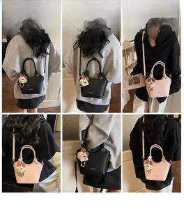 Detail view of stylish women's bucket bags in black and pink with teddy bear charm