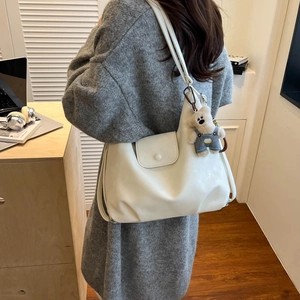 Close-up of white PU leather tote bag with a cute blue bear charm on a model's shoulder