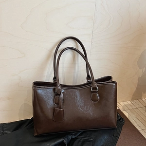 Detail view of dark brown tote bag with glossy oily texture and decorative hang tag