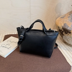 Detail of minimalist black leather tote bag featuring adjustable and detachable shoulder strap