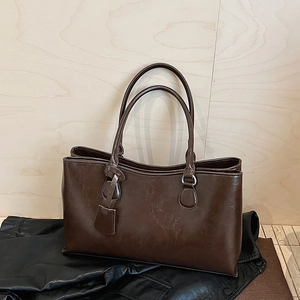 Detail of dark brown faux leather tote bag featuring silver metal rings and hanging tag