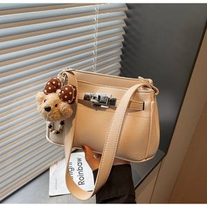 Detail of beige lychee pattern handbag with silver twist lock and cute bear charm
