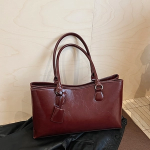 Detailed close-up of dark burgundy tote bag showing glossy texture and silver hardware
