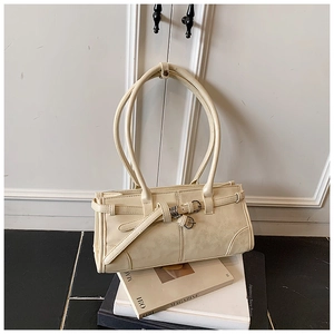 Détail d'un sac à bandoulière en cuir blanc crème avec longues anses doubles et boucles métal