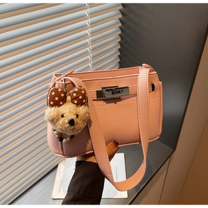 Close-up of pink litchi grain leather shoulder bag with silver twist lock and bear charm