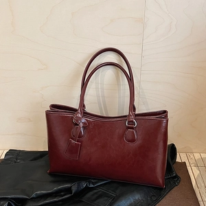 Detail of burgundy leather tote bag with sturdy handles on a black leather jacket background