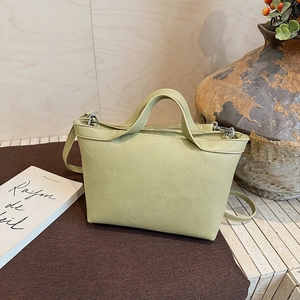 Pale green trapezoidal tote bag shown in a cozy setting with a vintage ceramic vase