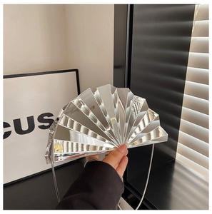 Detail of a silver fan-shaped clutch with mirror finish and metallic chain strap