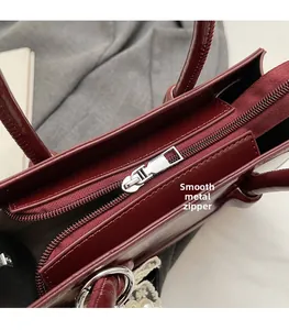 Close-up of smooth silver metal zipper and hardware on the burgundy crossbody bag