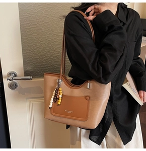 Detailed macro view of the brown lychee grain leather tote bag with colorful wooden beads