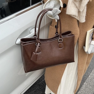 Close-up of a dark brown glossy leather tote bag with fine texture and slim handle