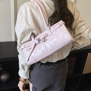 Détail d'un sac à bandoulière rectangulaire rose pâle avec boucles décoratives
