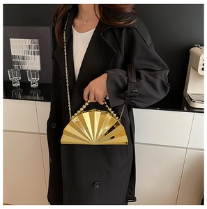 Detail of golden shell evening bag with pleated metal texture and beaded handle decoration