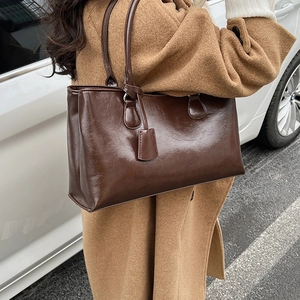 Deep brown oil wax leather tote bag shown on shoulder with elegant vintage texture