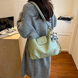 Detail of light green soft leather shoulder bag with a cute white bear plush pendant