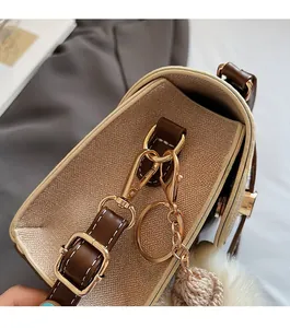 Detailed shot of golden metal hooks and hardware on a beige litchi leather crossbody bag
