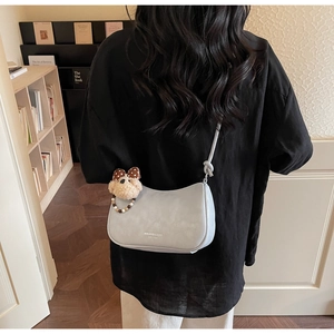 Close-up of light blue dumpling bag with knot strap and cute puppy plush charm accessory