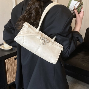 Détail d'un sac à bandoulière beige minimaliste avec boucle métallique et lanière décorative