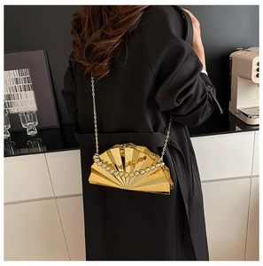 Detail of a gold pleated shell evening clutch with pearl handle and metal chain strap