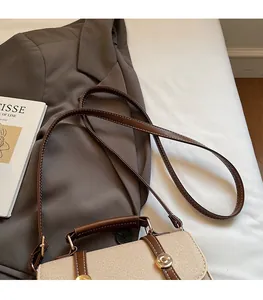 Close-up of canvas crossbody bag featuring brown leather trim and golden metal lock
