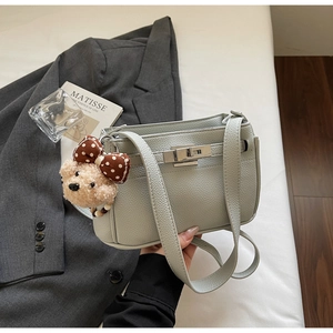 Detail of mint green lychee grain leather bag with silver buckle and cute bear charm