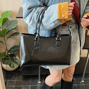 Model wearing a minimalist black leather tote bag showing the size and premium texture