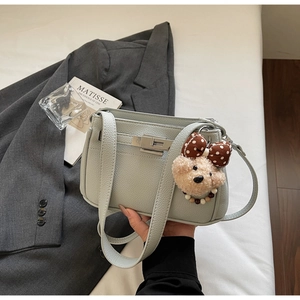 Close-up of light blue lychee pattern leather shoulder bag with silver lock and bear pendant