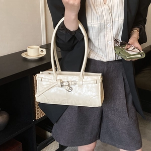 Détail de la texture en cuir plissé blanc crème et de la boucle métallique sur le sac à bandoulière