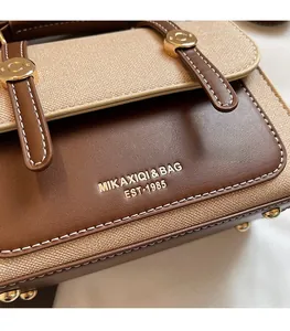 Detail of vintage brown leather patchwork bag with gold lettering and metallic buckles