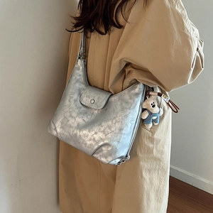 Detail view of silver cracked texture shoulder bag with cute plush bear keychain charm