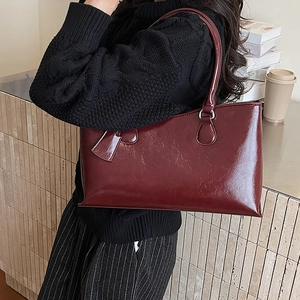 Detailed view of glossy dark red shoulder bag with fine oil-wax texture and silver hardware