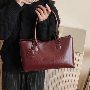 Close-up of premium dark red tote bag featuring vintage oily leather texture and twin handles