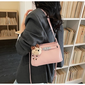 Detail of pink lychee leather shoulder bag with silver turn-lock and plush bear charm