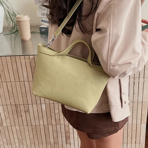 Detailed view of pale green tote bag showing smooth leather texture and metal strap clasp