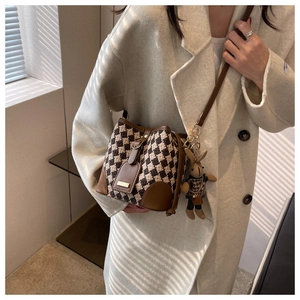 Détail du sac seau vintage à carreaux avec garniture en cuir brun et breloque lapin