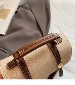 Close-up of beige fabric shoulder bag with brown leather handles and gold metal accents