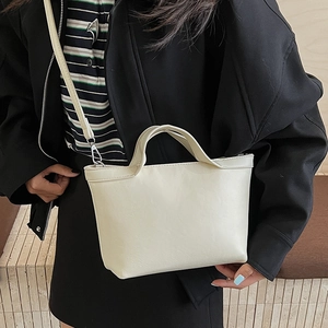 Detail of minimalist cream PU leather tote bag showing top handle and adjustable strap