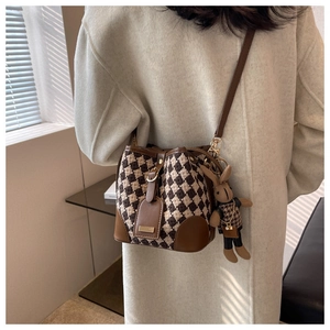 Détail du sac seau à motif pied-de-poule avec bordure en cuir et pendentif lapin