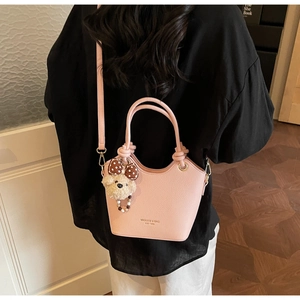 Pink bucket bag with litchi texture featuring a cute teddy bear charm and bow detail