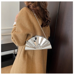 Close-up of a silver shell-shaped evening bag with pearl trim and fine metal chain strap