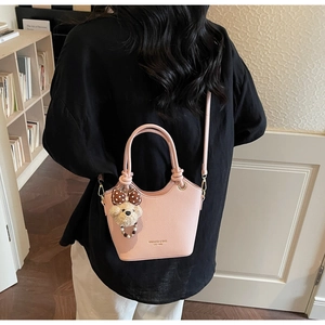 Pink lychee grain leather bucket bag with top handle and cute plush bear charm detail