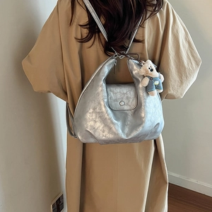 Detail of silver metallic crescent bag with adjustable straps and cute bear charm