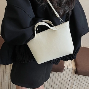 Detail view of cream leather tote bag featuring matte finish and silver hardware accents